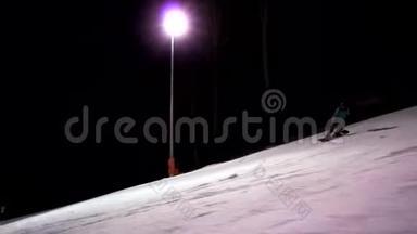 女子滑雪板的慢动作独自沿着滑雪道<strong>进行</strong>侧视。 配有照明的滑雪道。 女孩